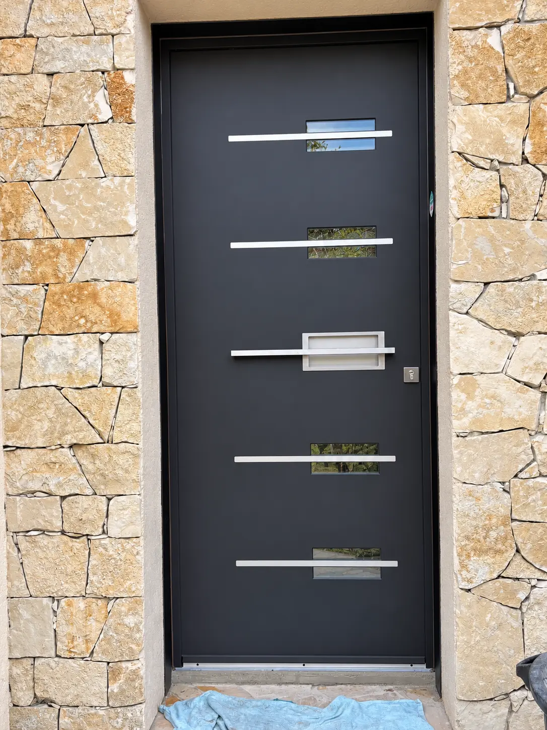 Détail d’une porte anthracite avec vitrages et inserts horizontaux