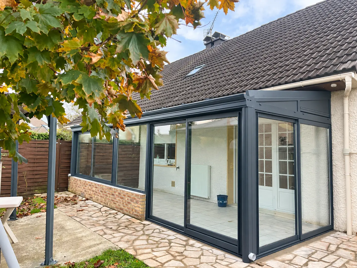 Véranda aluminium avec soubassement en briques et toiture vitrée