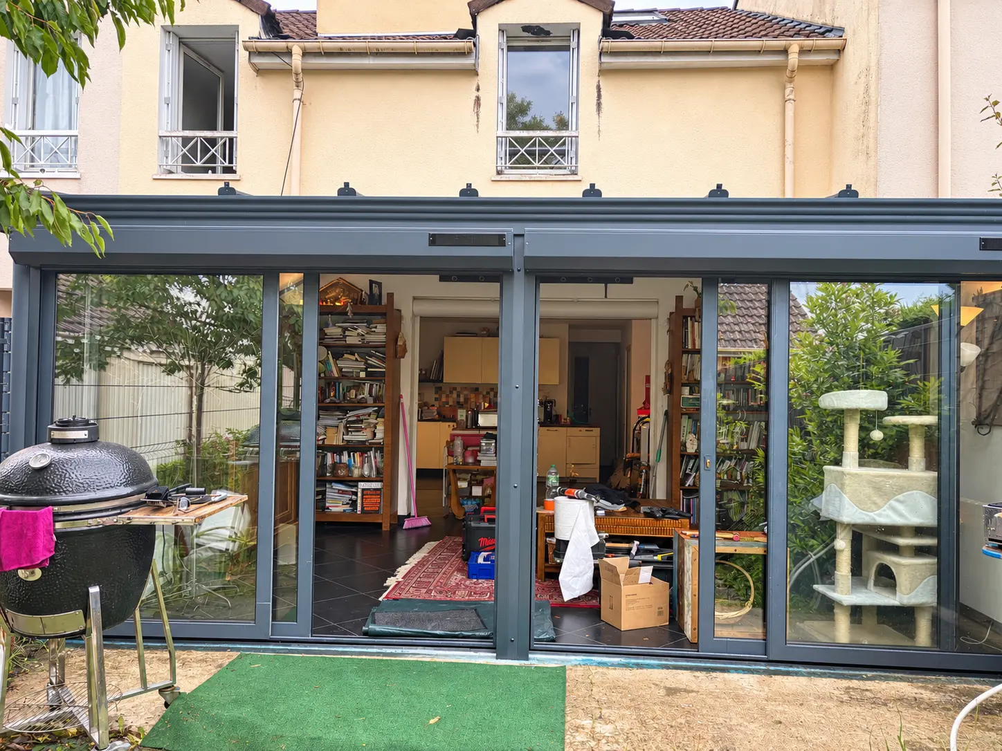 Véranda avec baies coulissantes ouvertes sur une pièce de vie